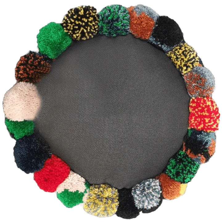 Colourful pom-pom wreath on grey background.
