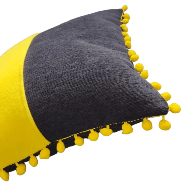Yellow pom-pom trimmed grey cushion.